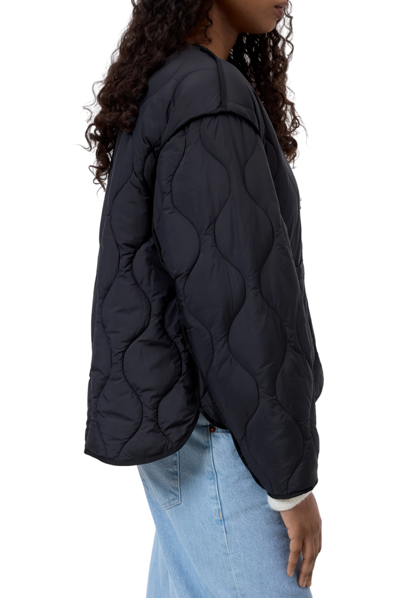 Dettaglio laterale della jacket trapuntata Closed nera con trapuntatura a onde, indossata su jeans azzurri