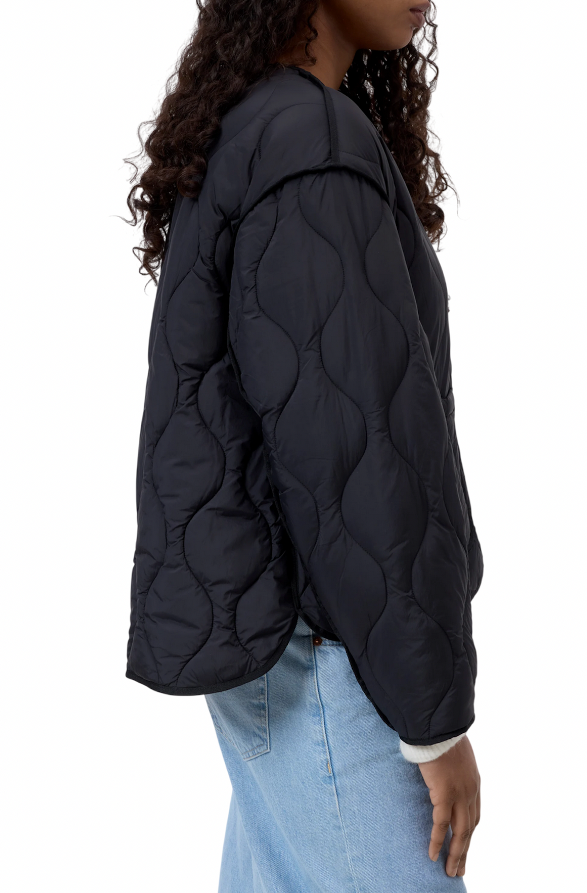 Dettaglio laterale della jacket trapuntata Closed nera con trapuntatura a onde, indossata su jeans azzurri